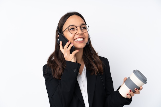 Giovane donna di telemarketer sul caffè bianco della tenuta da portare via e su un cellulare