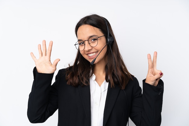 Giovane donna di telemarketer sulla parete bianca che conta sette con le dita