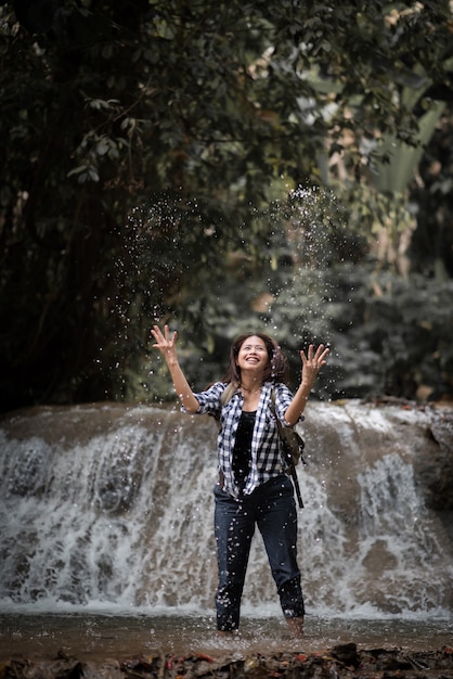 Giovane donna divertendosi sotto le cascate nella foresta