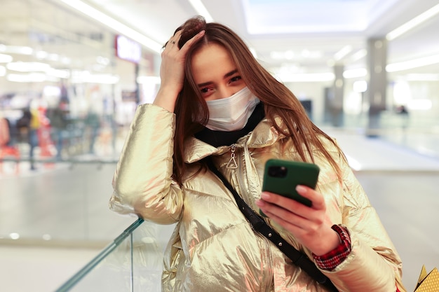 Giovane donna dopo lo shopping digitando sul suo telefono in un centro commerciale