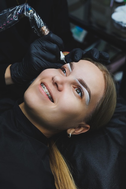 Giovane donna durante la procedura di mappatura professionale delle sopracciglia prima del trucco permanente