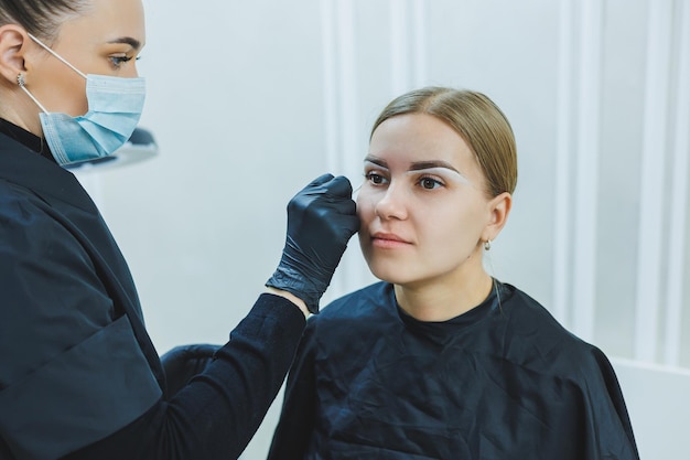 Giovane donna durante la procedura professionale di mappatura delle sopracciglia prima del trucco permanente