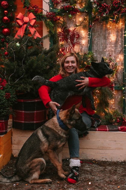 Giovane donna e i suoi cani in decorazioni natalizie