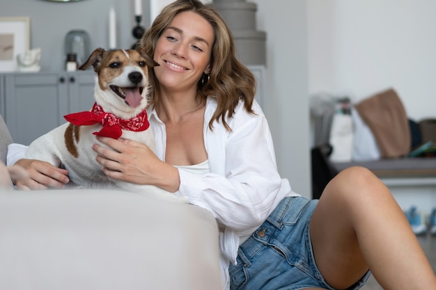 Giovane donna e il suo cane sul divano di casa. Adorabile animale domestico.