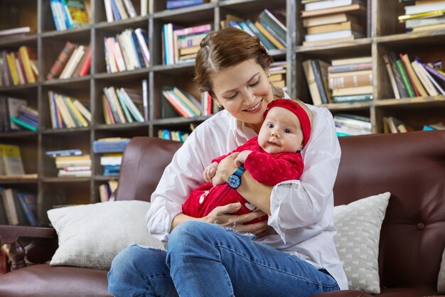 Giovane donna e la sua bambina sul divano in biblioteca a casa