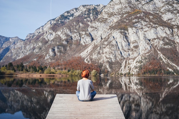 Giovane donna è seduta sul ponte di legno della bellissima natura intorno al lago di Bohinj in Slovenia Il Parco Nazionale del Triglav Alpi Giulie Slovenia