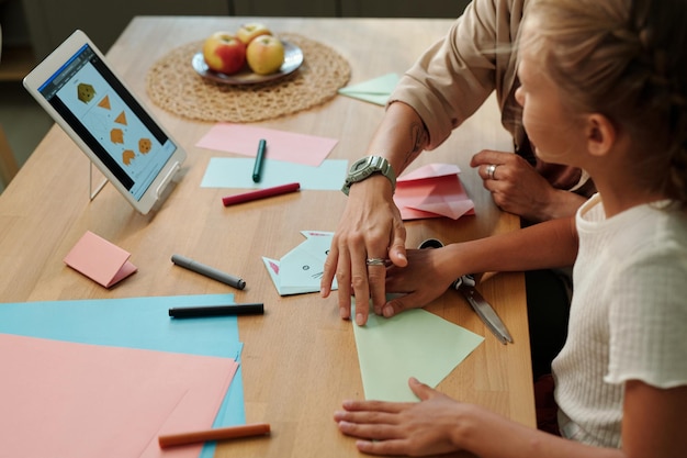 Giovane donna e sua figlia che imparano a fare origami a loro piacimento