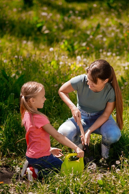 Giovane donna e sua figlia che piantano alberi nel parco