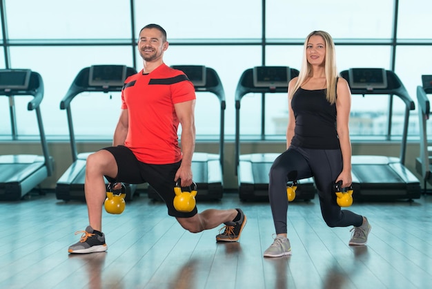 Giovane donna e uomo che fa esercizio con il bollitore in palestra