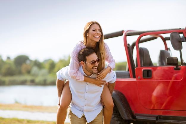 Giovane donna e uomo che si diverte all&#39;aperto vicino auto