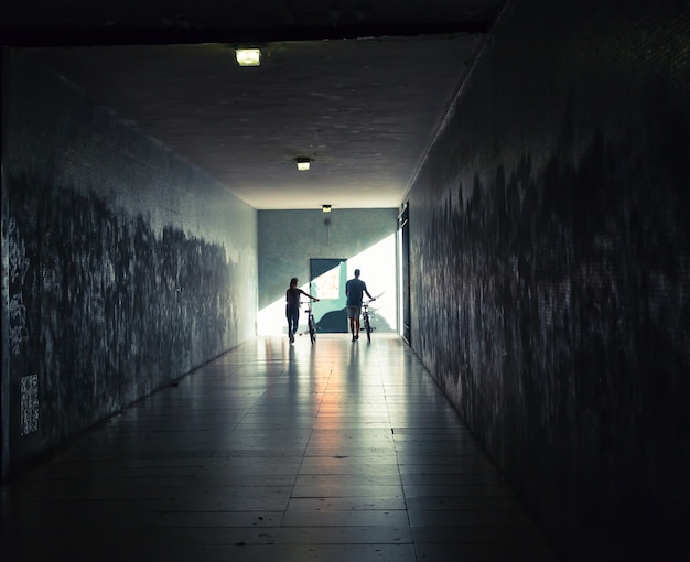 Giovane donna e uomo con le biciclette nel tunnel sotterraneo