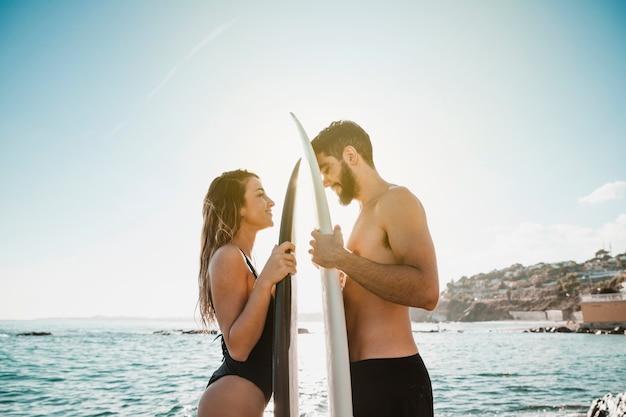 Giovane donna e uomo con tavole da surf vicino al mare