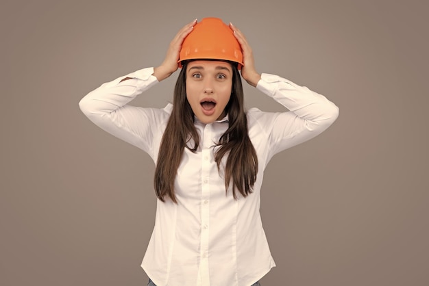 Giovane donna eccitata responsabile della costruzione Donna builder ritratto isolato con protezione casco wow Sfondo grigio