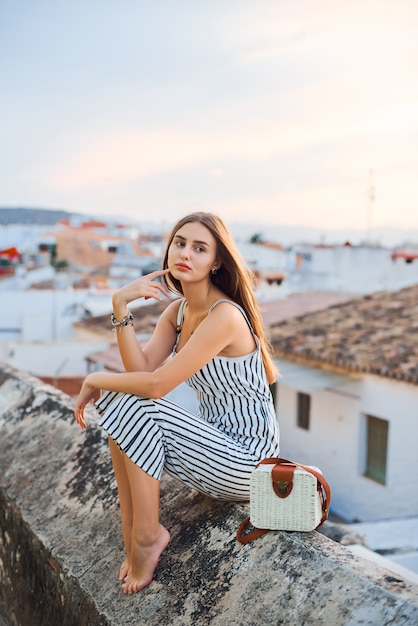 Giovane donna elegante a piedi nudi in posa sulla strada.