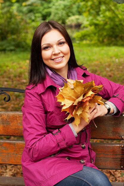 Giovane donna elegante con foglie d'autunno