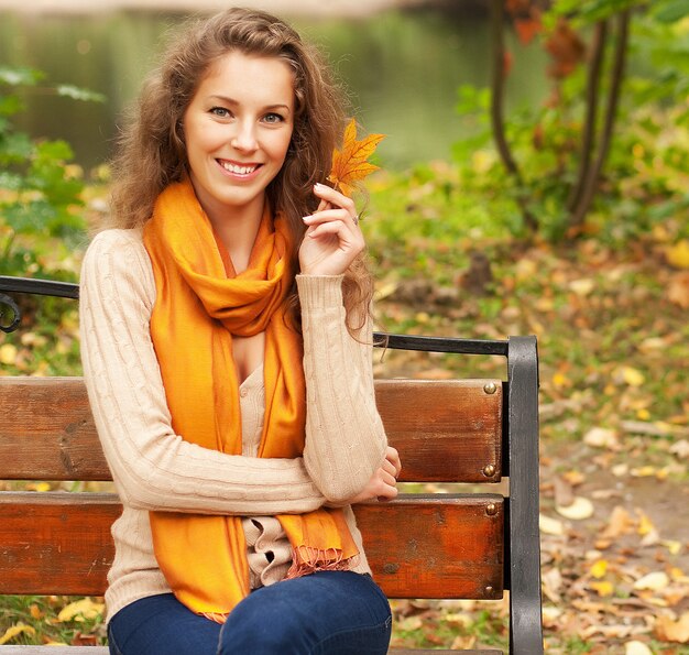 Giovane donna elegante con foglie d'autunno