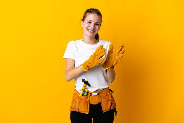 Giovane donna elettricista isolata su sfondo giallo che applaude dopo la presentazione in una conferenza