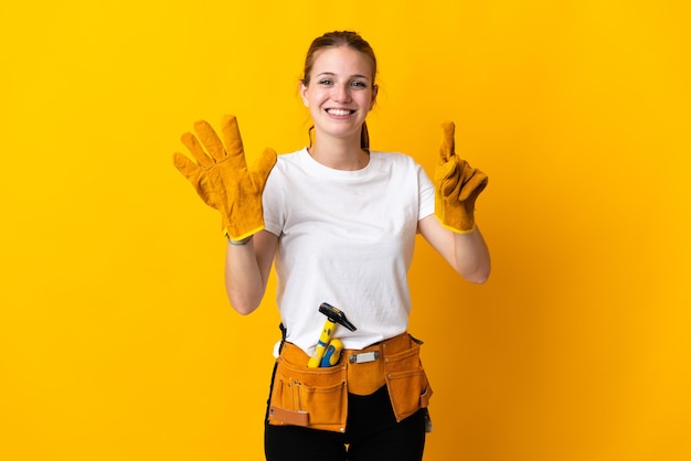 Giovane donna elettricista isolata su sfondo giallo che conta sei con le dita