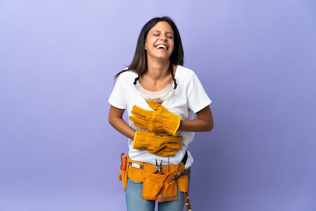 Giovane donna elettricista isolata su viola sorridente molto