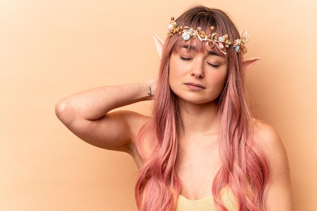 Giovane donna elfo con capelli rosa isolati su sfondo beige che tocca la parte posteriore della testa pensando e facendo una scelta