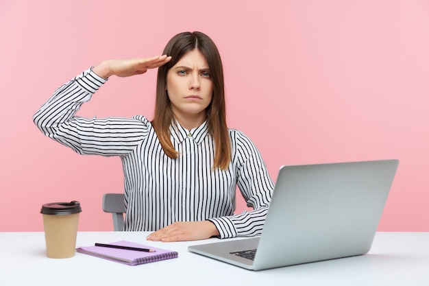 Giovane donna emotiva che si siede e che lavora in ufficio con sfondo rosa