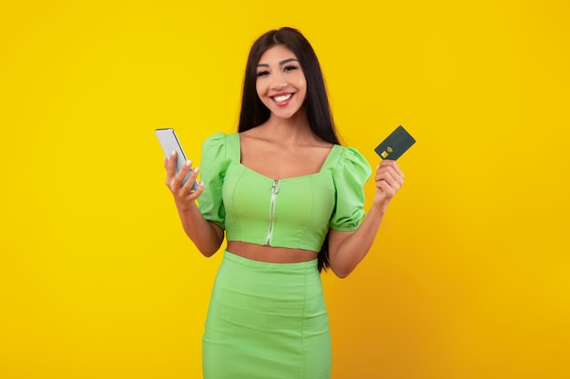 Giovane donna emozionante che tiene carta di credito e cellulare