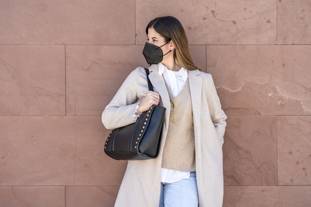 Giovane donna esecutiva con maschera e borsa nera.