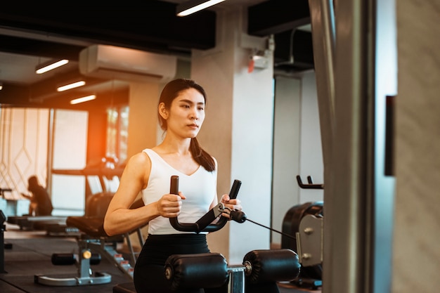 Giovane donna esile che risolve sull'apparecchiatura di addestramento nella palestra di forma fisica