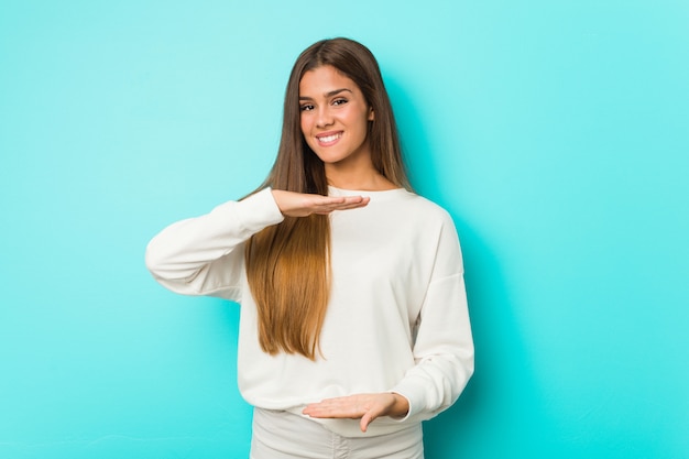 Giovane donna esile che tiene qualcosa con entrambe le mani, presentazione del prodotto.