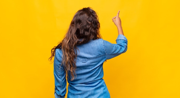 giovane donna espressiva in posa sul muro giallo yellow