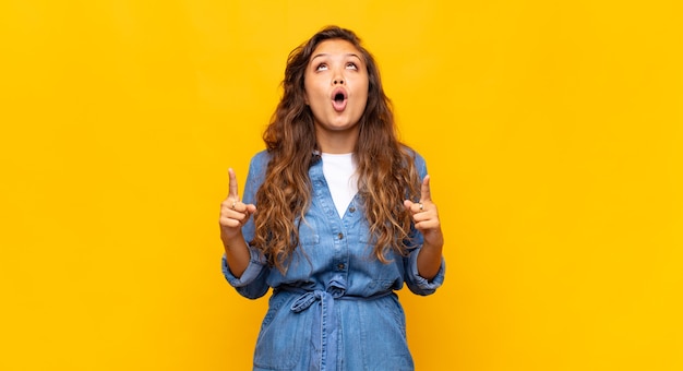 giovane donna espressiva in posa sul muro giallo yellow