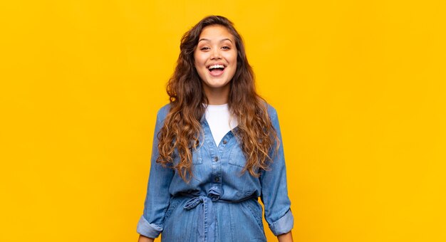 giovane donna espressiva in posa sul muro giallo yellow