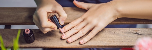 Giovane donna fa manicure con smalto gel e lampada uv in tonalità rosa banner formato lungo