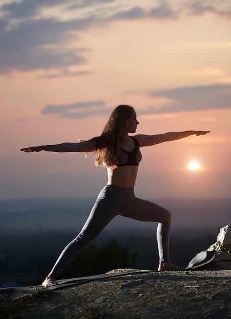 Giovane donna facendo esercizi di yoga all'aperto al tramonto