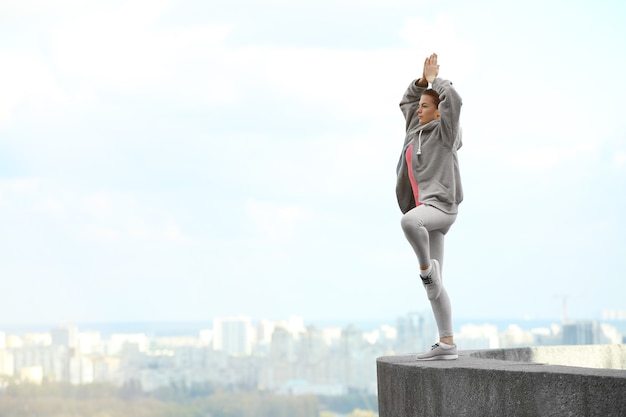 Giovane donna facendo esercizi di yoga sullo sfondo della città