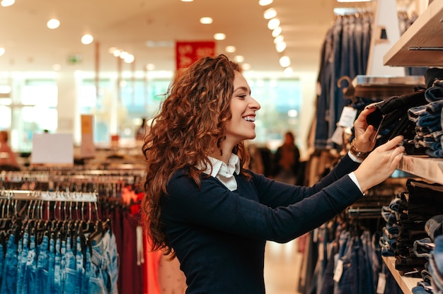 Giovane donna facendo shopping e scegliendo i vestiti.