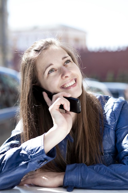 Giovane donna felice che chiama al telefono per strada