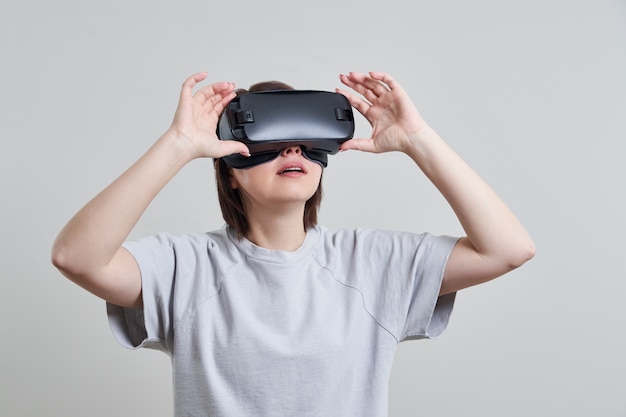 Giovane donna felice che gioca sui vetri di VR dell'interno, concetto di realtà virtuale con la giovane donna divertendosi con gli occhiali di protezione della cuffia avricolare, con lo spazio della copia