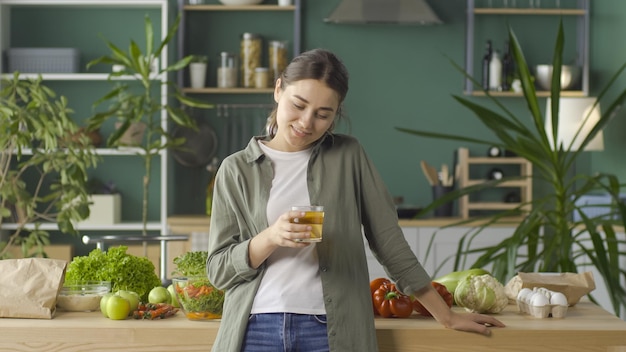 Giovane donna felice che gode del succo appena spremuto utilizzando prodotti biologici