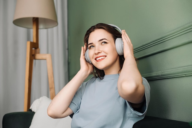 Giovane donna felice che indossa cuffie wireless che ascolta musica mentre si diverte a passare del tempo libero su th