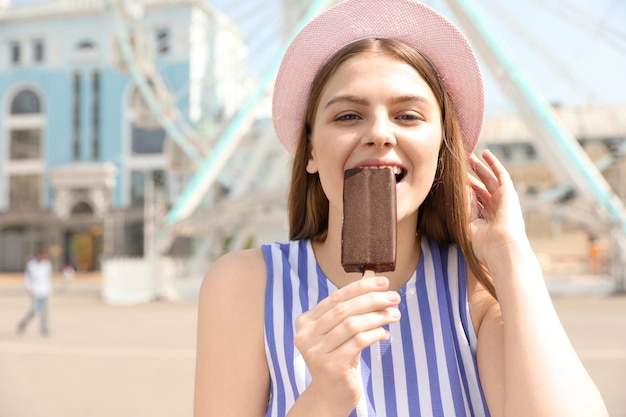 Giovane donna felice che mangia il gelato nel parco divertimenti Spazio per il testo