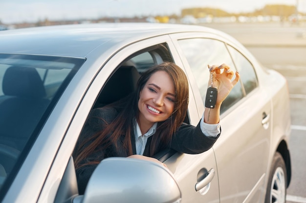 Giovane donna felice che mostra la chiave della nuova auto