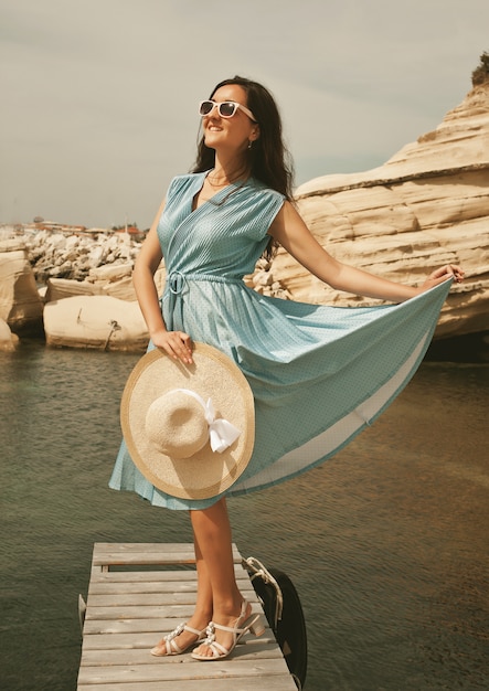 Giovane donna felice che posa vicino al mare