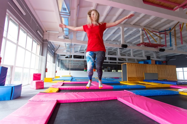 Giovane donna felice che salta su un trampolino al chiuso.