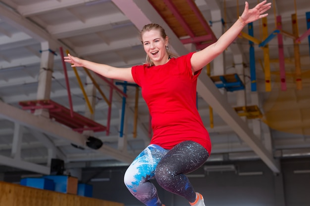 Giovane donna felice che salta su un trampolino al chiuso.