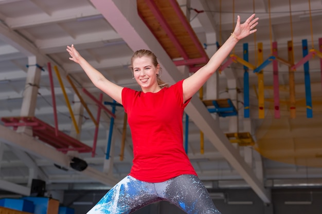 Giovane donna felice che salta su un trampolino al chiuso.