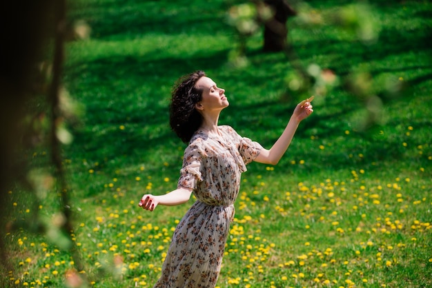 Giovane donna felice che si siede sull'erba nel parco della città di estate.