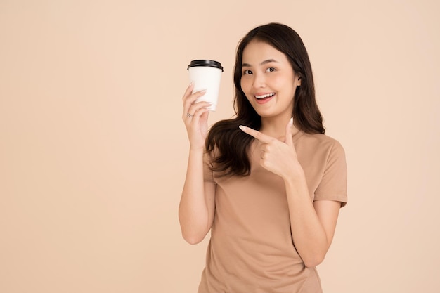 Giovane donna felice che tiene tazza di caffè in piedi in studio