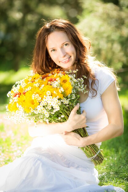 Giovane donna felice che tiene un mazzo di fiori primaverili all'aperto