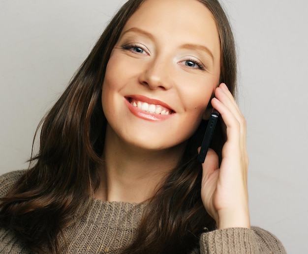 Giovane donna felice che utilizza un telefono cellulare isolato su uno sfondo bianco